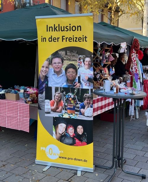 Infostand zur Vereinsgründung - großer Aufsteller im Vordergrund mit Motto: Inklusion in der Freizeit